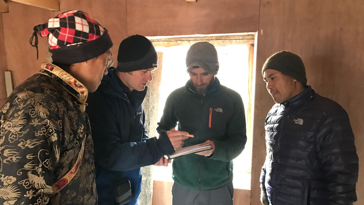 A group of Tetra Tech and Community Action Nepal employees take notes inside a building in Chispoani, Nepal