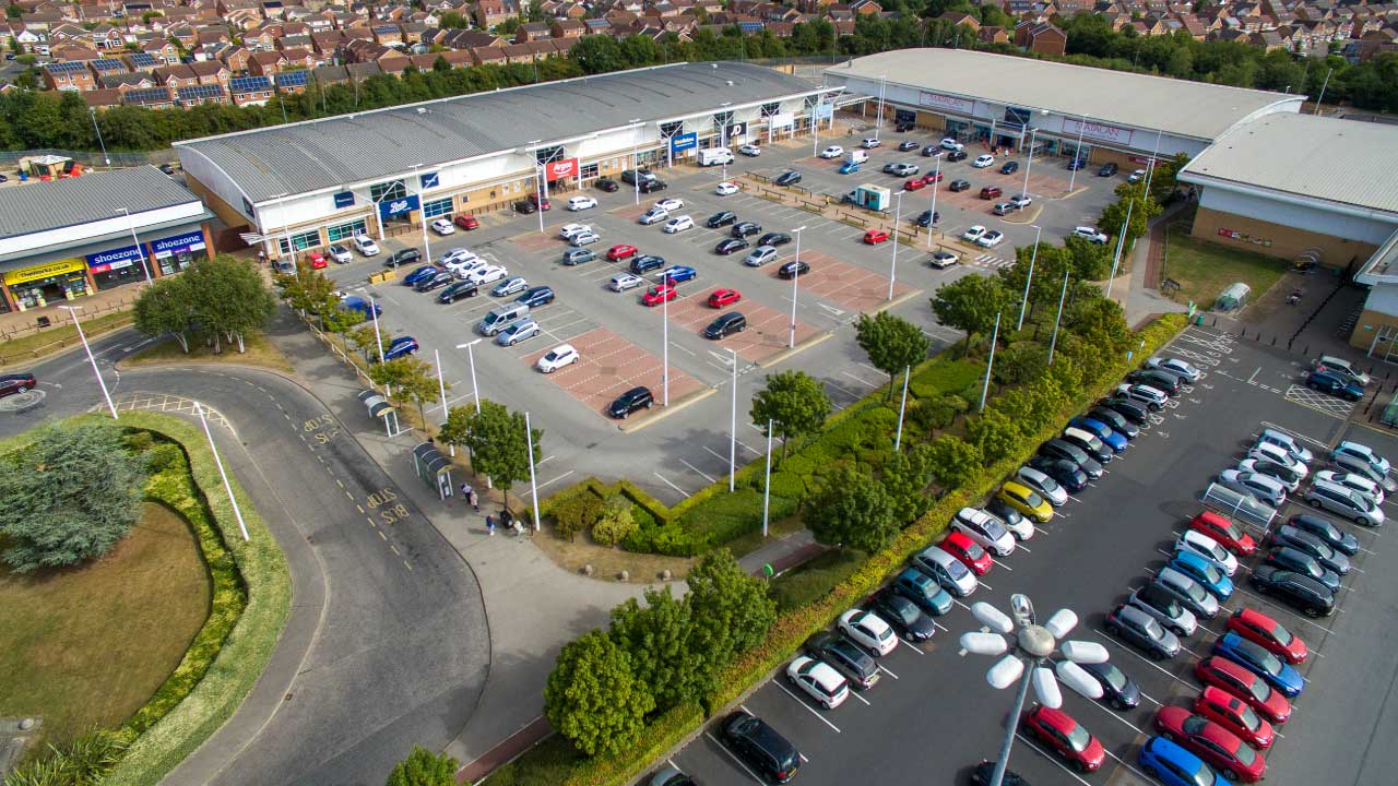 Aerial view of a retail park and parking lot surrounded by residential homes