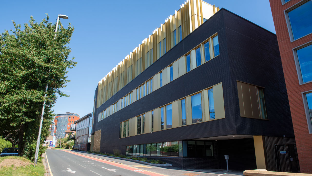 Wide shot of a three-story black and gold university building