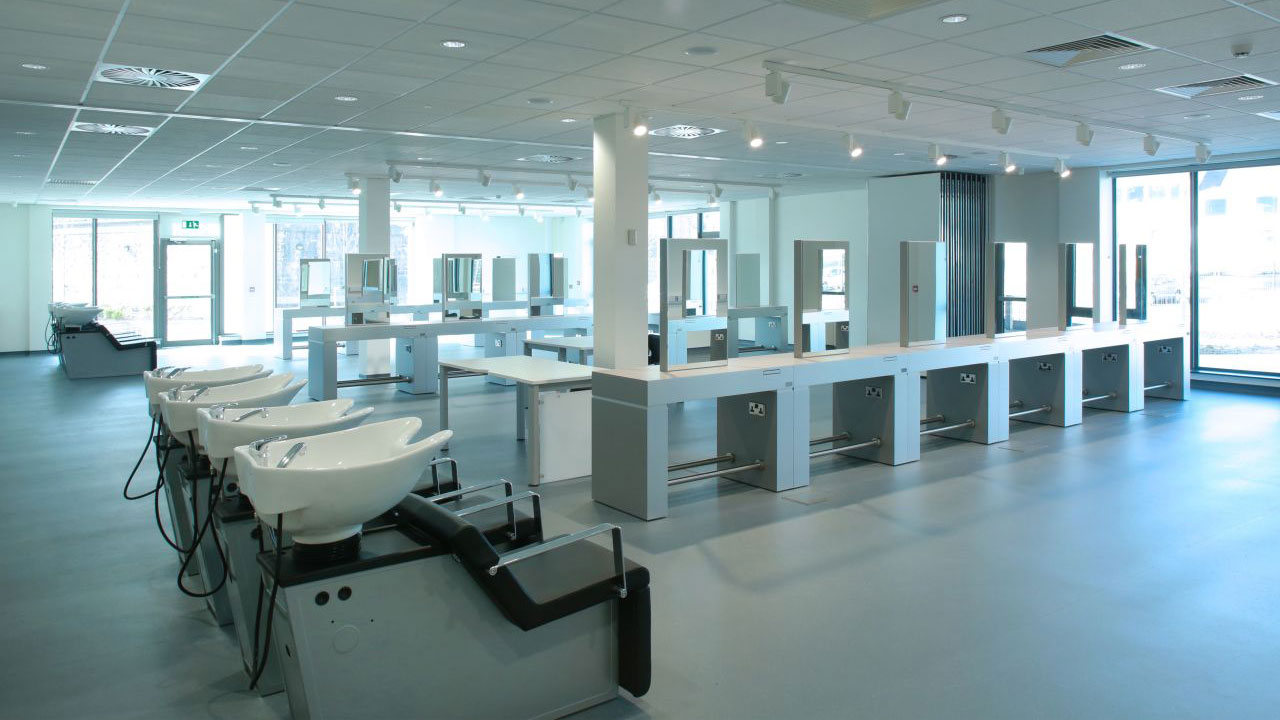 Large classroom for cosmetology students featuring salon shampoo sinks and vanities