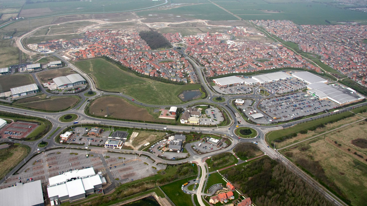 Aerial view of a big neighborhood with long curling streets, rotundas, and big parking lots