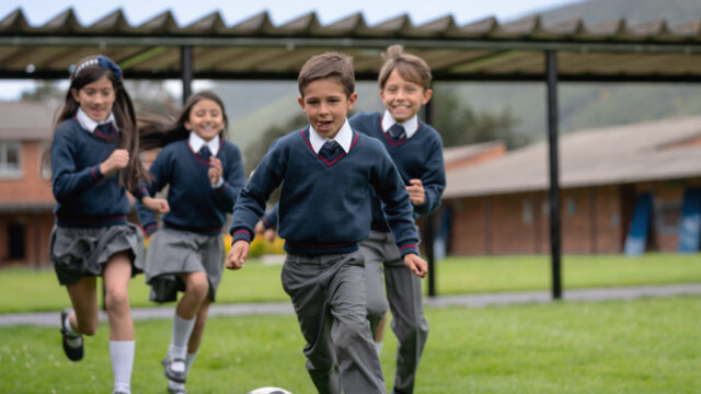 A group of 4 children chasing a football