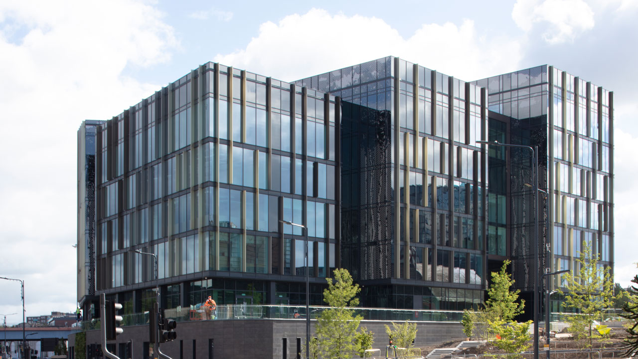 Wide shot of a building in the middle of a city covered with reflective windows