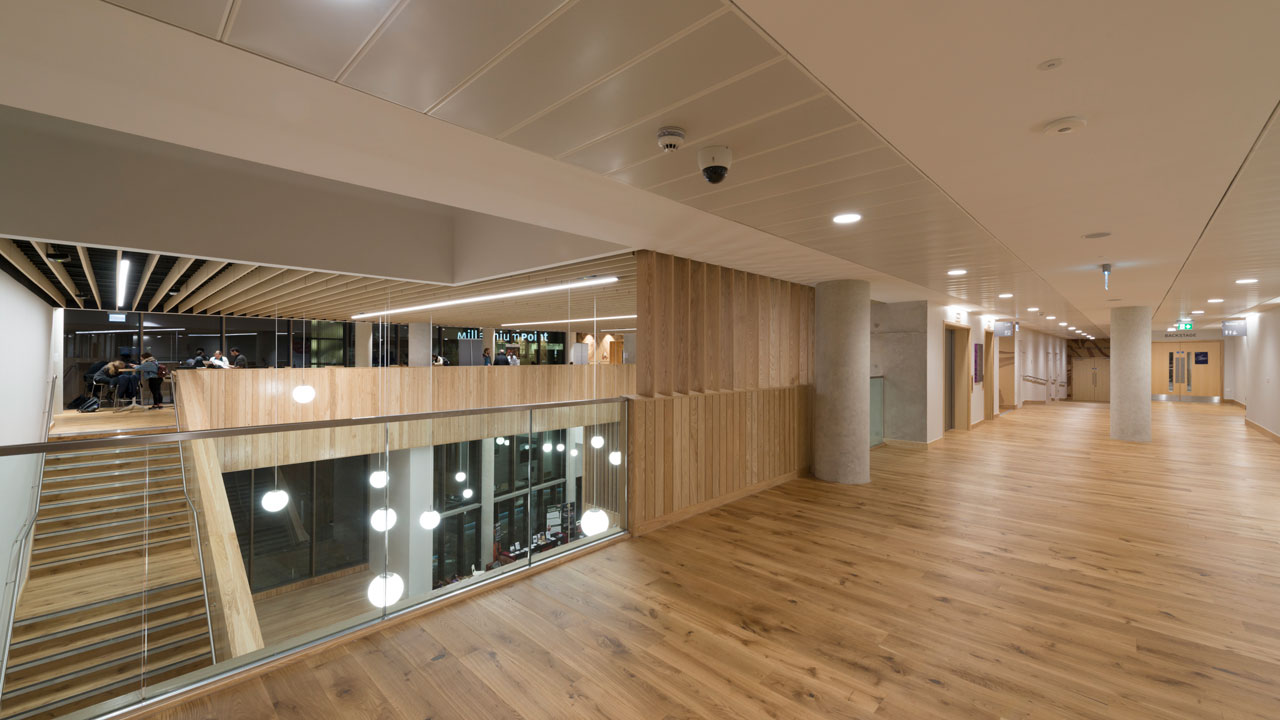 Second-floor room with glossy wooden floors and view of wooden staircase to left