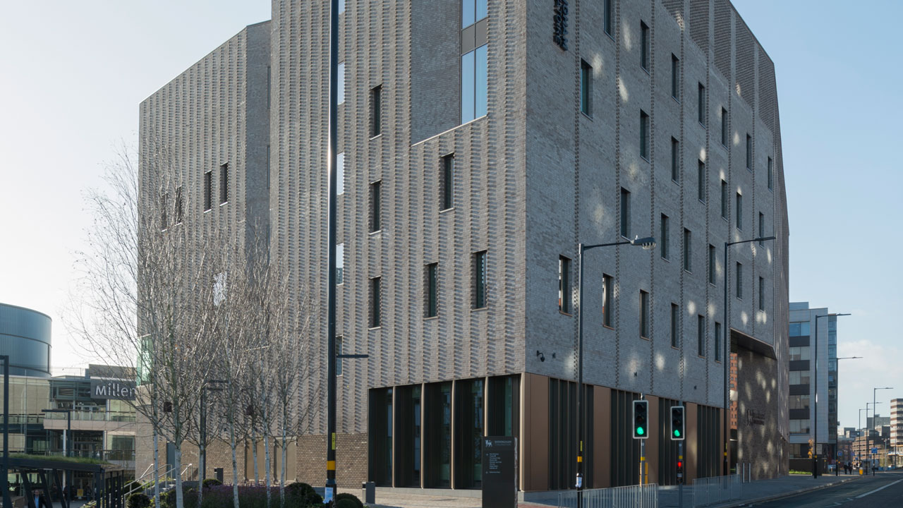 Tall gray multi-story building with exterior lights reflecting