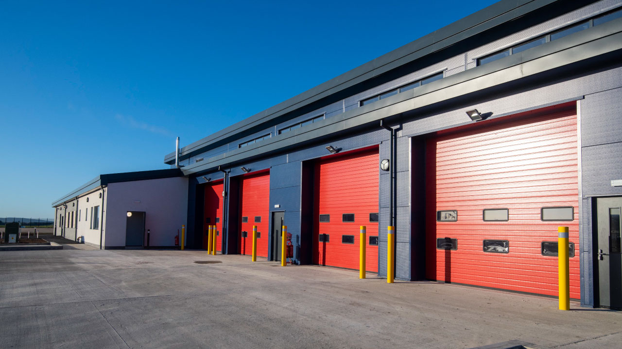 New fire station with paved driveway and four bright red garage doors