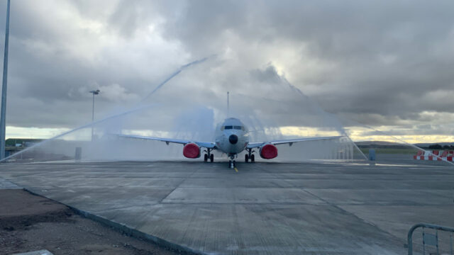 A white aeroplane being hosed down by water jets on a runway