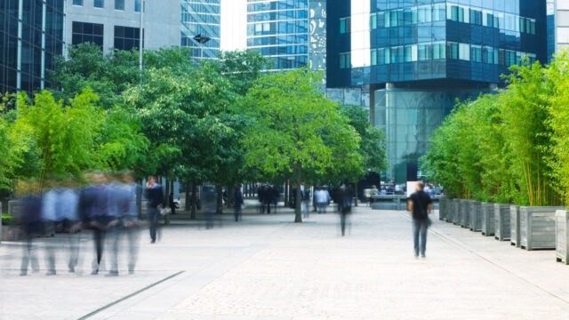 Blurred images of people walking amid business buildings and trees