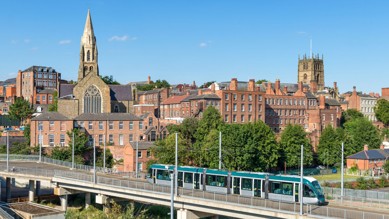 NET tram passes over elevated tracks in front of redbrick buildings and church cathedral