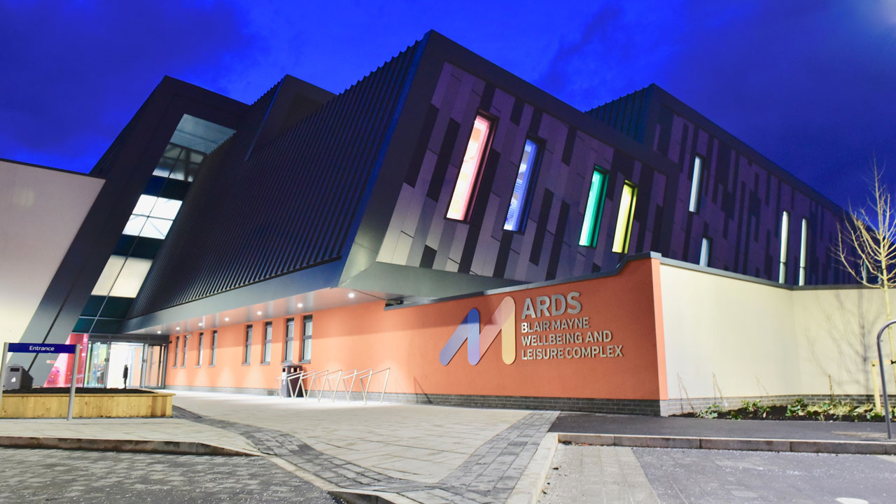 Exterior view of the modern style sports hall building in the evening, with good lighting both indoors and outdoors