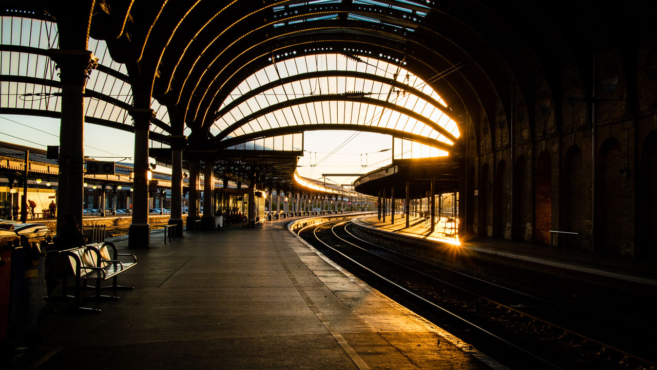View of the train tracks beneath the train station canopy at sunset