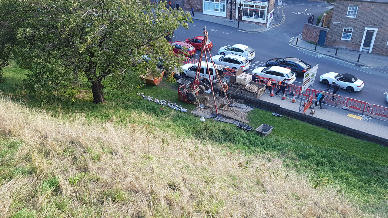 A hillside next to a road, fenced off during active site investigation works