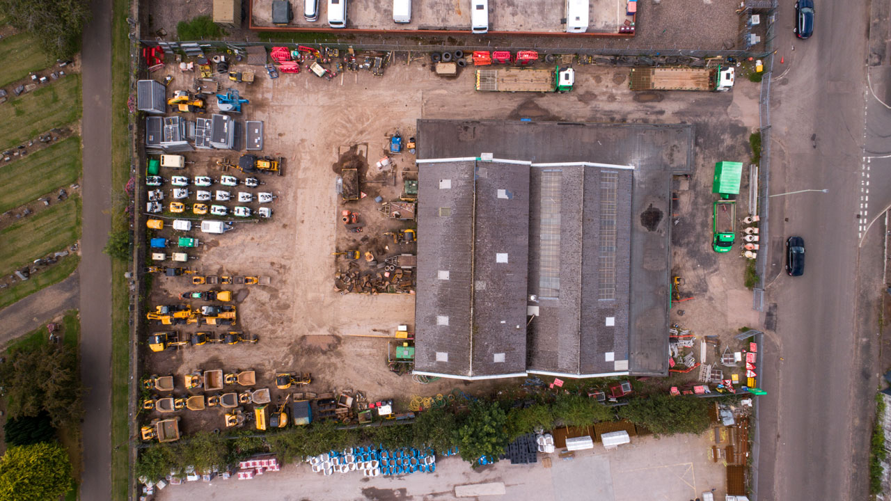 Aerial view of the warehouse and vehicle-filled parking lot of a construction company