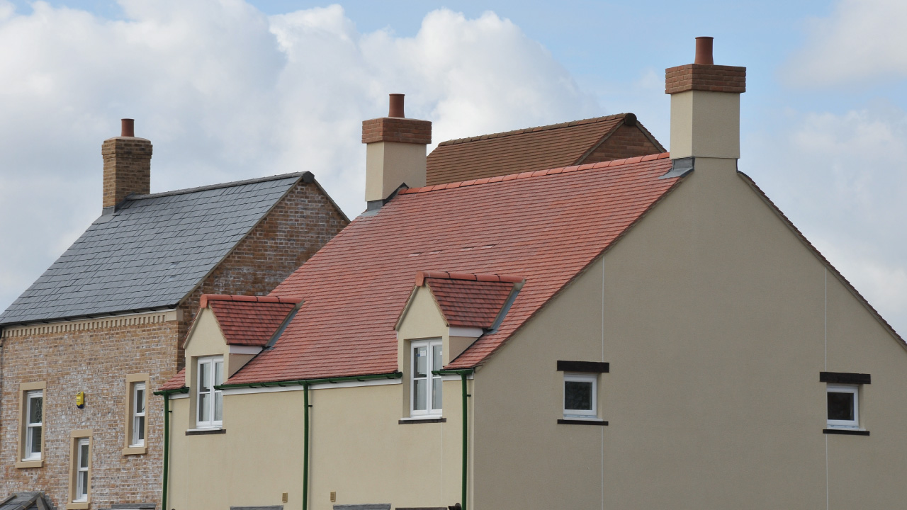 A red tiled roof building with two other tiled roof buildings in the background