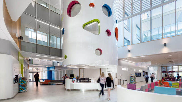 A large indoor hospital pillar with colorful shapes carved into it