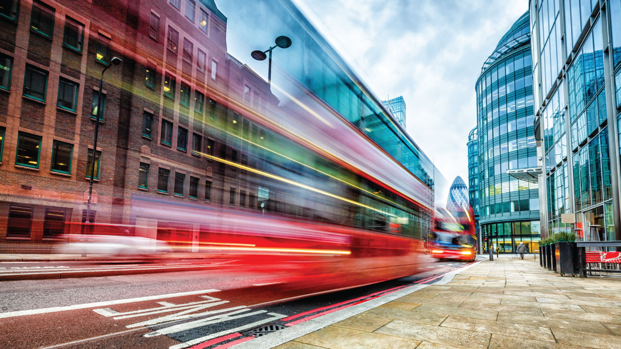 A long exposure of a city street with a red bus in motion