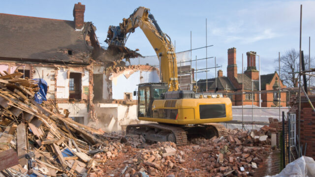 A yellow excavator demolishing a building