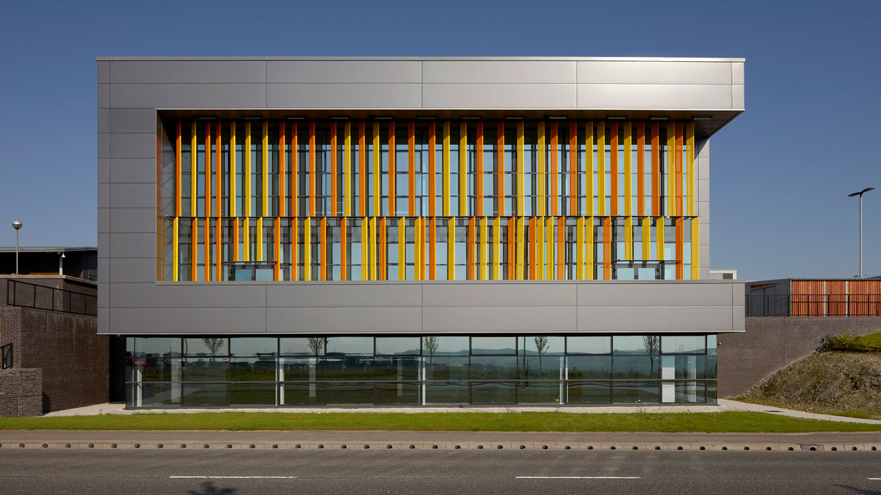 Front view of a silver modern building with decorative yellow and orange panels