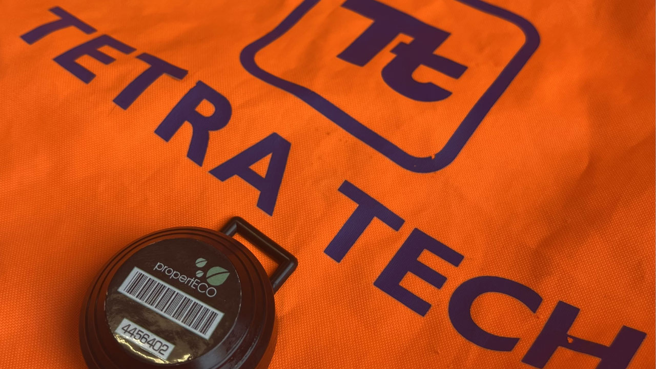 The Tetra Tech logo on an orange vest with a radon monitor on top